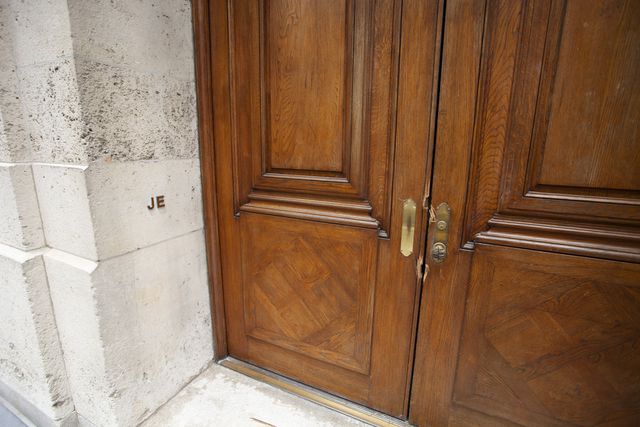 Closeup picture of Jeffrey Epstein's front door, with damaged door from the federal raid, and the Initials J and E on the side